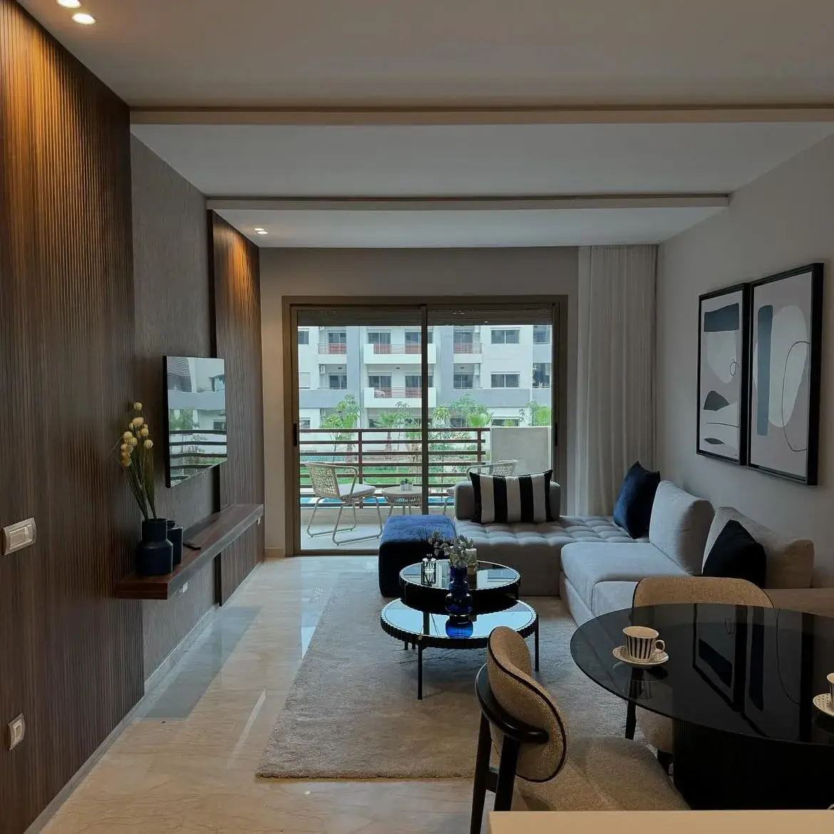 Salon ouvert contemporain avec canapé d'angle, panneau TV en bois et coin repas — aménagement intérieur YASMINA HOME